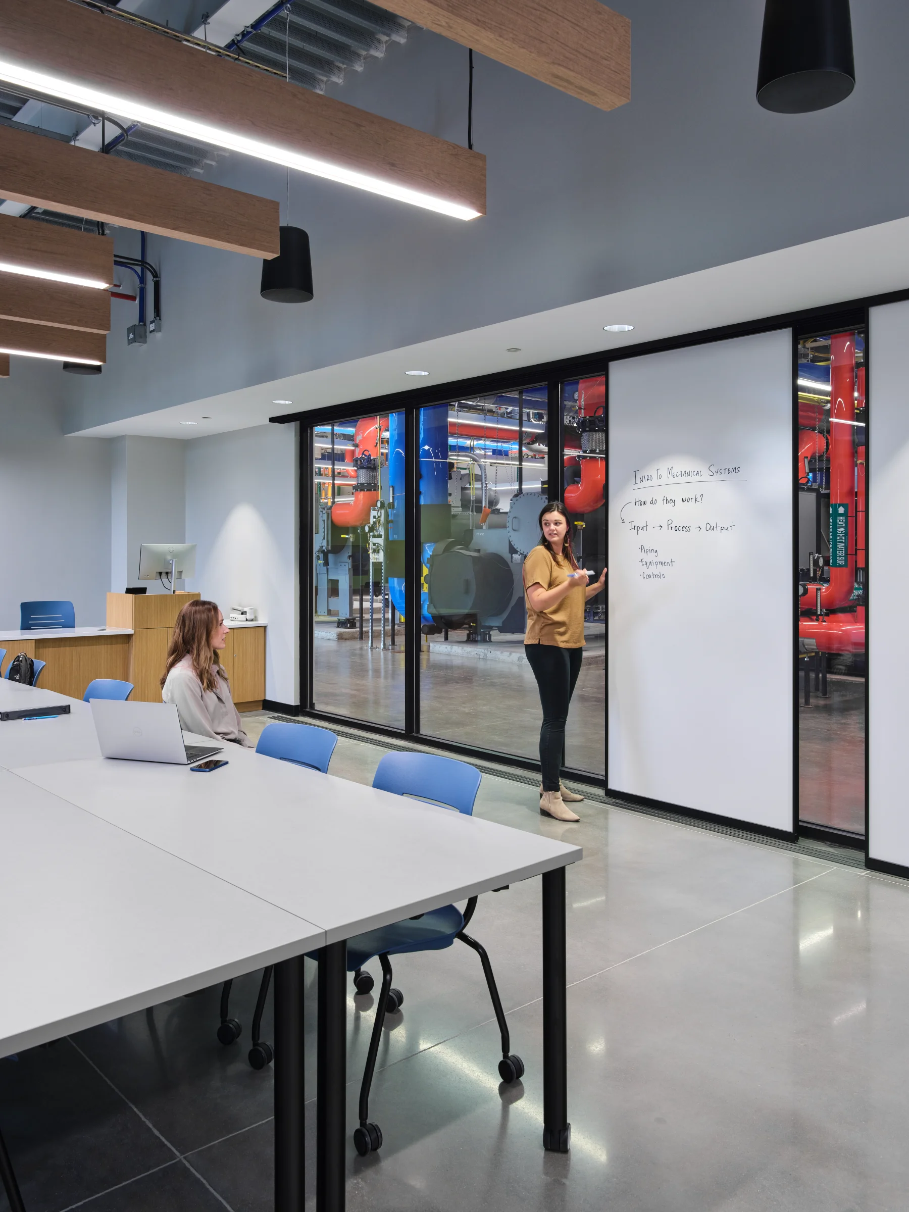 A classroom with a large dry erase board inside of the Central Energy Plant by HH Architecture