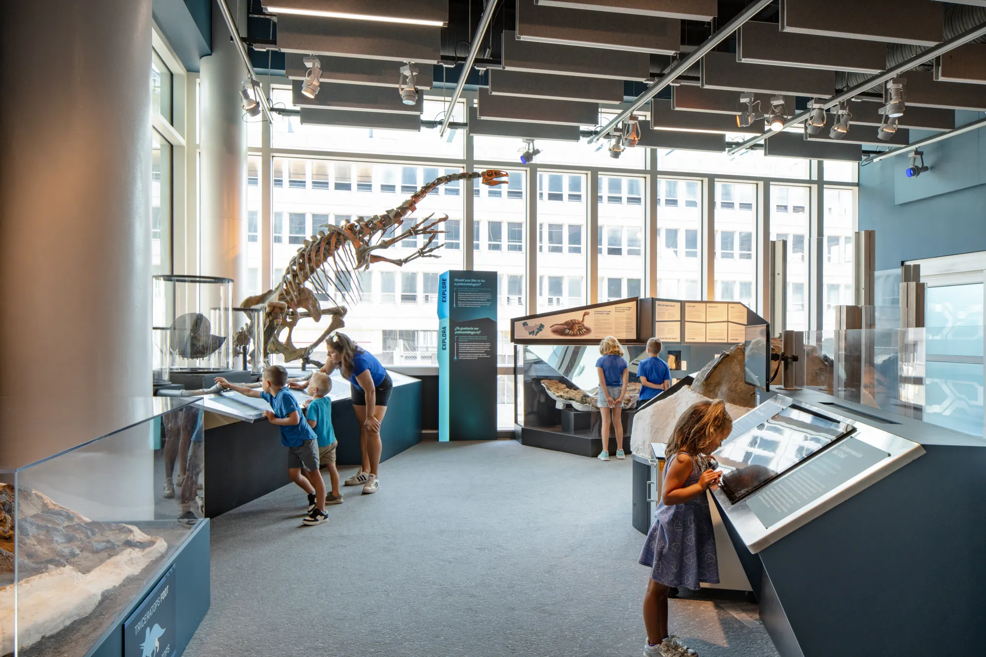 Museum guests reading and observing the Dueling Dinosaurs Laboratory Exhibit at the North Carolina Museum of Natural Sciences